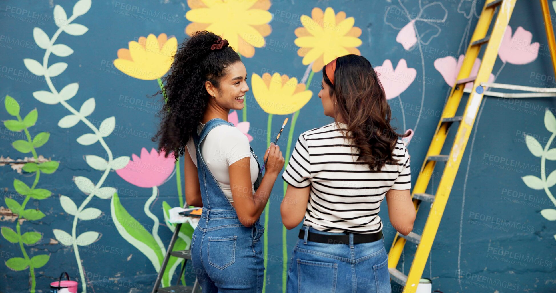 Buy stock photo Conversation, women and painting mural for wall, ladder or community project with artistic expression. People, outdoor or friends with creativity, volunteer or diy decor with flowers or student hobby