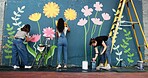 Artist, women and painting mural on wall for sustainable awareness, environmental activism or creative project. Flower art, back or volunteer group with floral decor for earth day design and teamwork