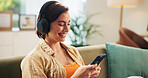 Woman, phone and headphones on sofa, smile and texting in home with streaming, audio and relax in lounge. Girl, smartphone and happy with mobile app for listening to music on couch at apartment