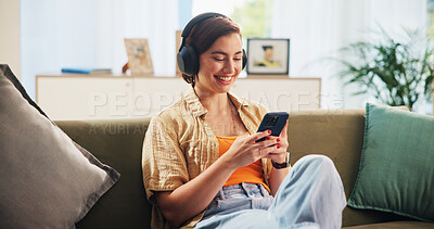 Buy stock photo Woman, phone and headphones on sofa, happy and texting in home with streaming, audio and relax in lounge. Girl, smartphone and smile with mobile app for listening to music on couch at apartment