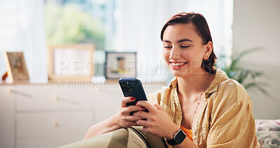 Buy stock photo Woman, happy and phone on sofa, relax and texting with funny meme in living room at apartment. Girl, person and smartphone with mobile app, comic video and smile on couch with social media in home