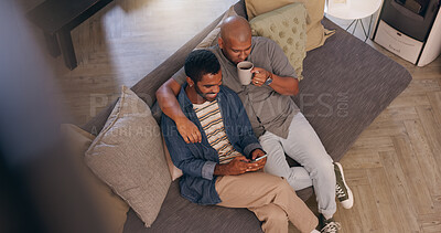 Buy stock photo Coffee, hug and phone with gay couple on sofa in living room of home together from above. App, break and social media with happy lgbt men embracing in apartment for browsing or romance on weekend