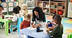 Drawing, education and teacher with children in classroom for learning, nursery and creative art. Growth, kindergarten and academy with woman and kids at school for helping and child development