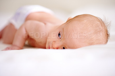 Buy stock photo Morning, tired and baby on bed for rest, relaxing and tummy time for nap with youth in nursery. Family, wake up and face of newborn in bedroom for child development, comfortable or wellness in home