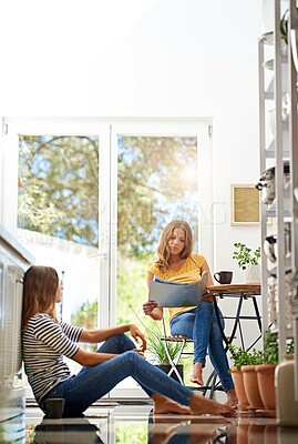 Buy stock photo Relax, reading and sisters together in kitchen with coffee for morning bonding, chat and newspaper. Women, twins weekend conversation with news, discussion and sitting in home for social connection.