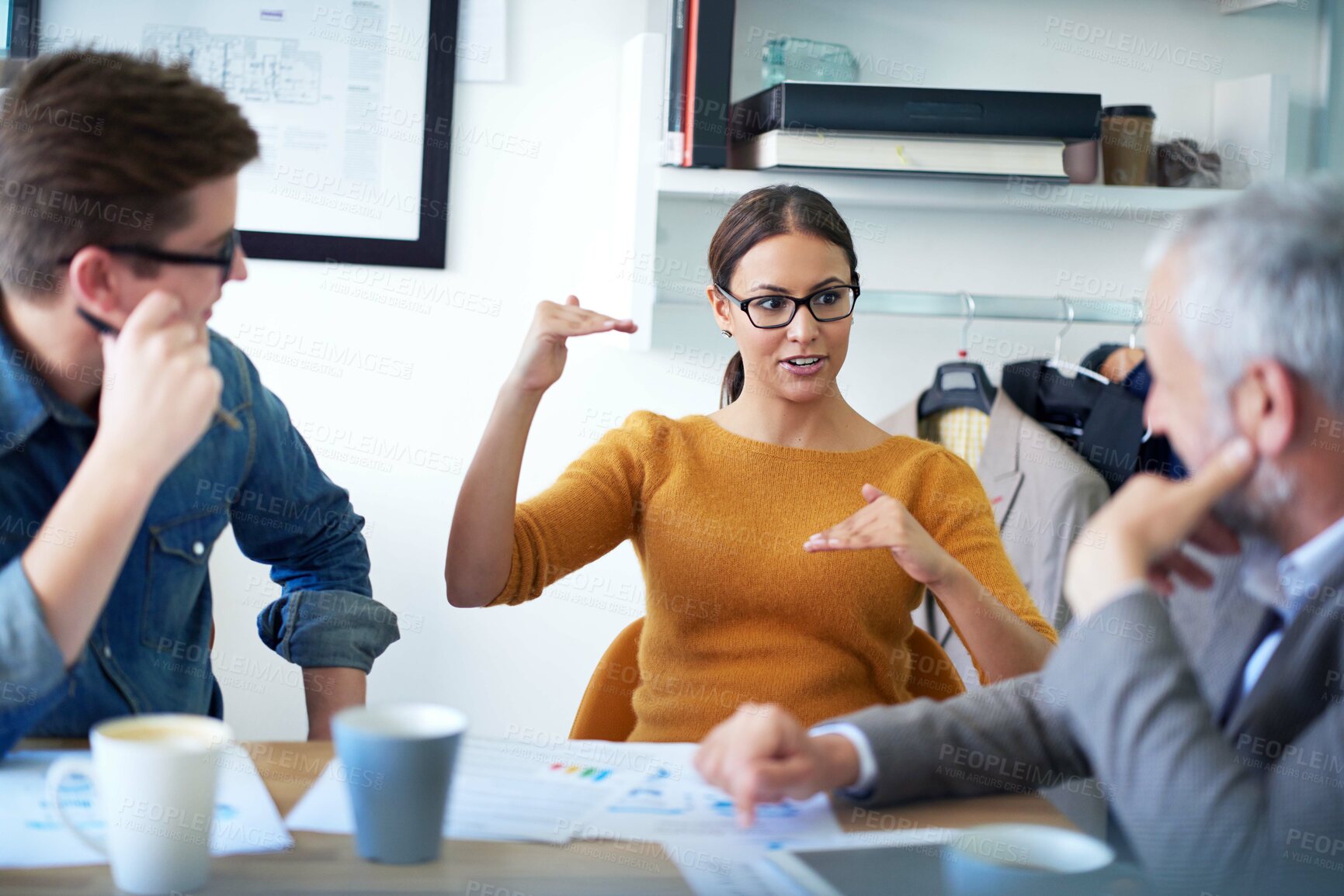 Buy stock photo Shot of a young businesswoman explaining something to her colleagues in a meeting