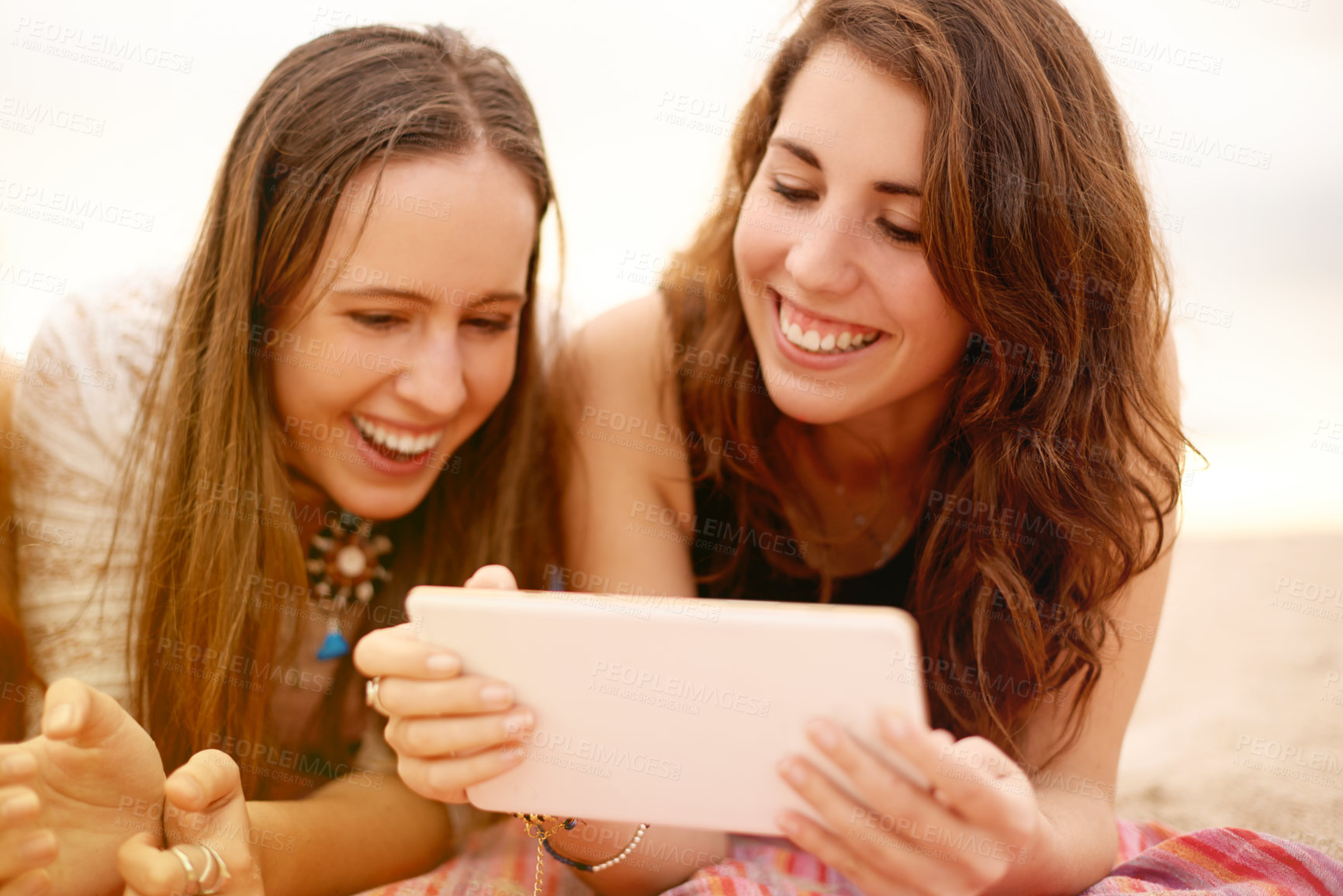 Buy stock photo Women, tablet and laugh with friends for social media, communication and beach picnic. Female people, smile and lying on blanket with digital technology for summer holiday, vacation or ocean post