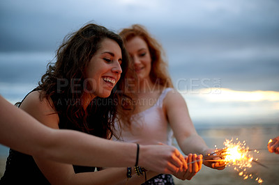 Buy stock photo Happy, woman and friends with sparklers on beach for reunion, social gathering and New years party. People, fireworks and celebration for tropical travel, festival vacation and sea sunset for bonding