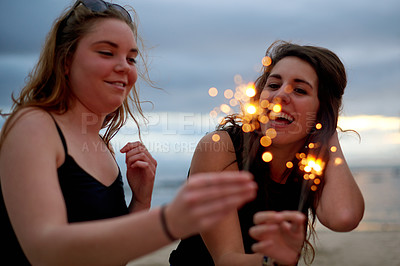 Buy stock photo Friends, happy and sparklers on beach for celebration, social gathering and New Years party in evening. Sunset, women and fireworks at ocean for event, bonding and celebrate birthday at seaside