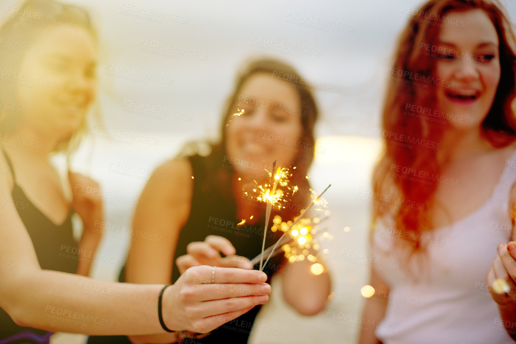 Buy stock photo Beach, women and friends with sparklers, celebration and bonding together with happiness. Group, ocean and vacation with tropical island, fireworks and excited with cheering, laughing and energy