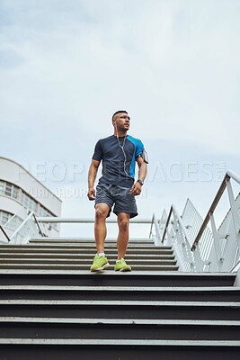 Buy stock photo Fitness, earphones and man on steps in city with health, wellness and streaming subscription. Urban workout, body care and runner listening to music, podcast or app on stairs for morning exercise.