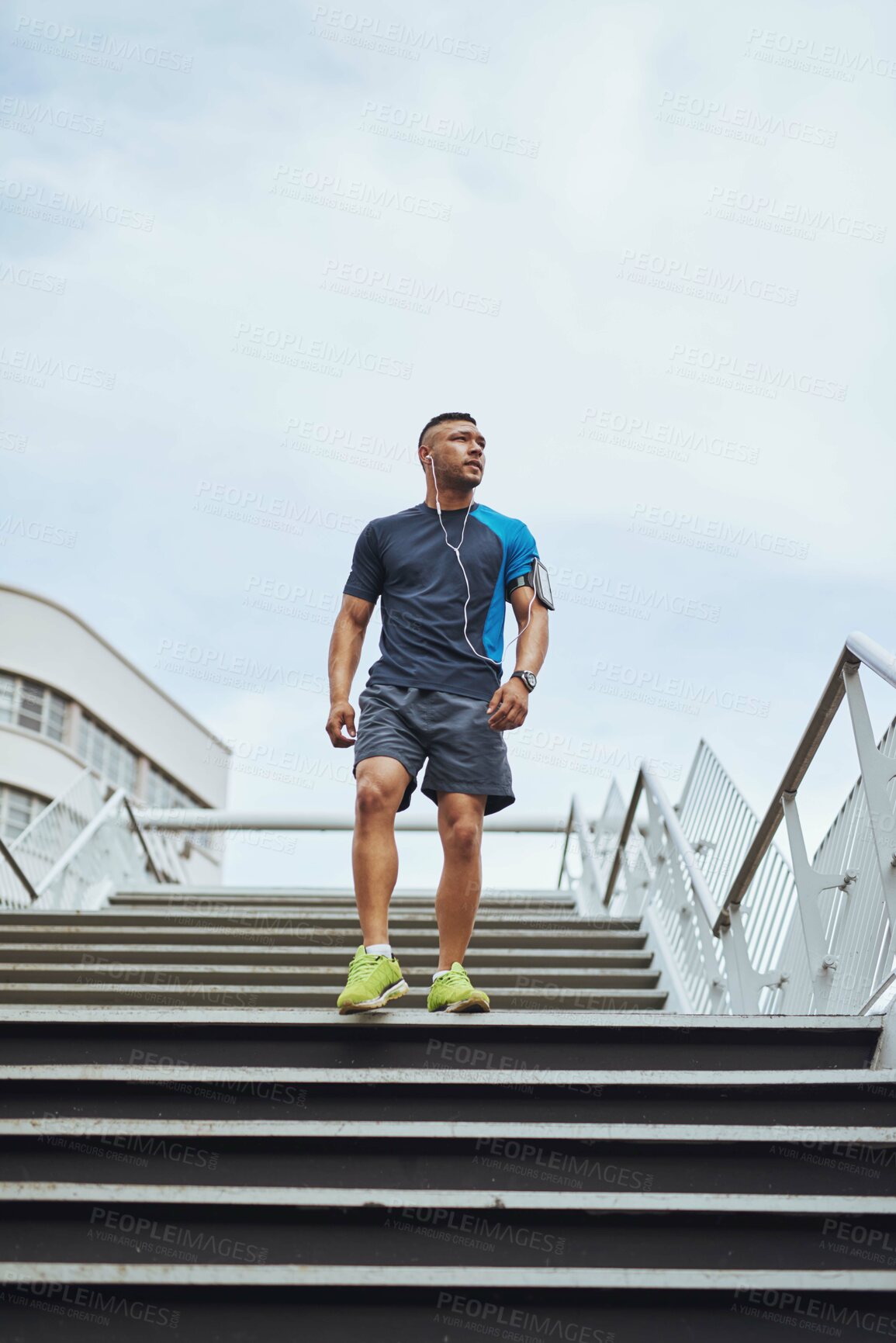 Buy stock photo Fitness, earphones and man on steps in city with health, wellness and streaming subscription. Urban workout, body care and runner listening to music, podcast or app on stairs for morning exercise.