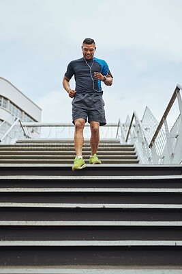 Buy stock photo Fitness, running and man on steps in city with health, wellness and earphones for streaming. Urban workout, body care and runner listening to music, podcast or app on stairs for morning exercise.
