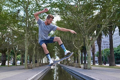 Buy stock photo Skateboard, jump and river with man in city for culture, extreme sports and trick flip. Fitness, hobby and street league with person training at canal for skating, ollie grind and balance practice