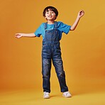 One cute mixed race child wearing casual clothes while having fun and being energetic against an orange copyspace background. Asian kid being active