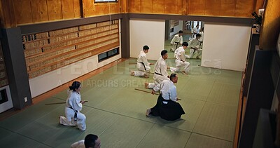 Buy stock photo Dojo, class and Aikido exercise group in gym with wood sword Japanese martial arts and fight in wellness studio. Learning, sport and bamboo weapon with people and strike practice for defence above