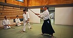 Dojo, class and mentor in Aikido training in gym with wood sword Japanese martial arts and fight exercise in wellness studio. Learning, sport and weapon with people and strike practice for defence