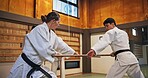 Dojo, class and strike partner at Aikido training in gym with wood sword Japanese martial arts and fight exercise in studio. Learning, sport and bamboo weapon with people and practice for defence