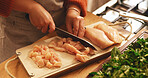 Hands, chicken and cutting board in kitchen, home and meal prep with knife, poultry and cooking healthy food. Person, chef and tools for organic meat, nutrition and diet for wellness at apartment