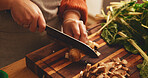 Hands, mushroom and cutting board in kitchen, home and meal prep with knife, spinach and cooking healthy food. Person, chef and tools for organic produce, nutrition and diet for wellness at apartment