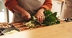 Hands, spinach and cutting board in kitchen, home and meal prep with knife, vegetables or cooking healthy food. Person, chef and tools for organic produce, nutrition or diet for wellness at apartment