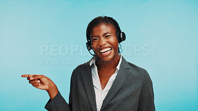 Buy stock photo Pointing, customer service and portrait of black woman in studio for announcement, online help and contact. Blue background, happy and person with headset for sales news, crm support and advice