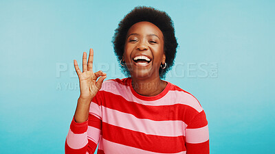 Buy stock photo Portrait, perfect and black woman in studio, smile or agreement on blue background. African person, face or happy model with hand gesture, funny or laughing with support, positive feedback or ok sign