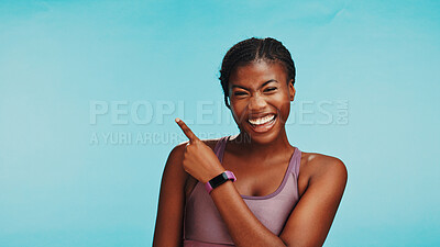 Buy stock photo Black woman, fitness and portrait in studio with pointing, sports announcement or happy with space. Personal trainer, smile or showing gesture on blue background for gym sign up promo or membership