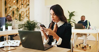Buy stock photo Phone, creative and business woman in office for email, notification and magazine editor typing review. Startup, mobile and serious manager online, reading article and check publication on laptop