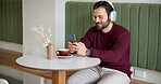 Man, headphones and phone in coffee shop for music, social media or typing in dating app. Customer, cafe and cellphone in restaurant for audio, communication or online networking with podcast