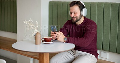 Buy stock photo Man, headphones and phone in coffee shop for music, social media or typing in dating app. Customer, cafe and cellphone in restaurant for audio, communication or online networking with podcast