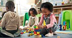 Education, child and playing with building blocks in classroom for creative activity, development or learning. Happy, girl student or stack toys at kindergarten for gross motor skills or coordination