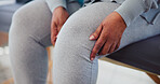 Person, hands and knee with leg injury for physiotherapy, arthritis or joint inflammation on bed at clinic. Closeup, patient or sore ache with pain for muscle tension, fibromyalgia or osteoporosis