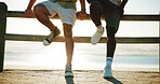 Men, legs and friends at beach for break with bonding, fashion shoes and support outdoor. Style, people and together on wood fence, travel or vacation to relax with connection in nature at sunset