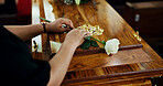 Hands, person and flower on coffin at funeral for farewell, mourning death and goodbye at burial ceremony. Sad, widow and rip with rose for casket respect, memorial service and emotional for loss