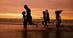 Silhouette, running and people at ocean for sunset, freedom and excited on summer vacation. Friends, energy and playing at beach space for travel holiday, adventure and splashing in water for fun
