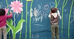 Wall, children and drawing with chalk for education, cognitive development and creativity in school. Back, students and kids with learning for writing mural, inspiration and outdoor in kindergarten