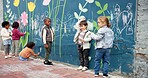 Kindergarten, children and drawing with chalk on mural wall for fun outdoor activity on playground. Kids, group or creative youth with art for childhood development or growth at elementary school
