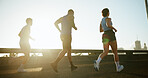People, running and sun in city for workout, cardio exercise or marathon together on road. Group, friends or runners with lens flare or sprint for physical activity, training or race in an urban town