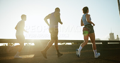 Buy stock photo People, running and sun in city for workout, cardio exercise or marathon together on road. Group, friends or runners with lens flare or sprint for physical activity, training or race in an urban town