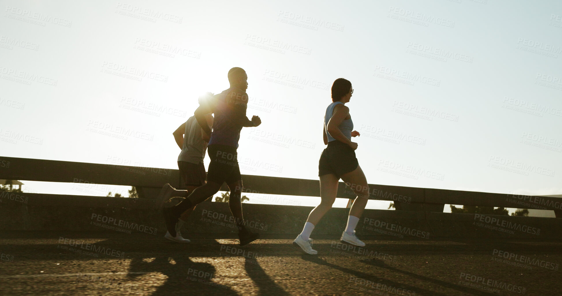 Buy stock photo People, back and running with sunshine in city for workout, exercise or training on road. Active group, friends or runners with bridge for sport, marathon or outdoor sprint together in an urban town