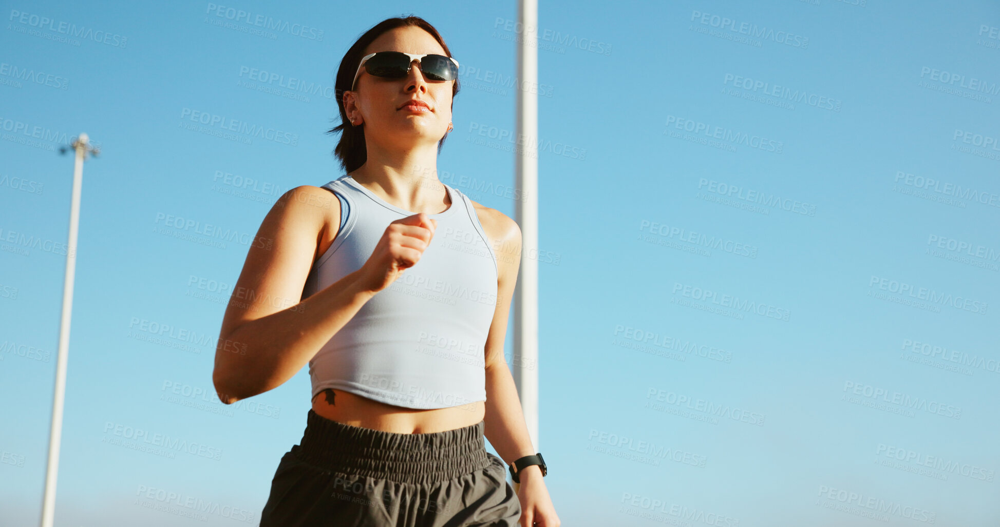 Buy stock photo Running, athlete and woman with sunglasses, outdoor and routine in morning for fitness and confident. City, runner and person with energy on urban street, blue sky and active for wellness or cardio