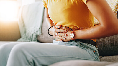 Buy stock photo Home, woman and hands with pain for stomach, menstrual cramps and discomfort on sofa in living room. Closeup, female person and ache on couch for colon inflammation, abdomen health and constipation