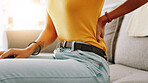 Woman, hand and back pain with injury on sofa for discomfort, muscle tension or strain at home. Closeup, female person or ache with sore spine for pressure, bad posture or bruise on couch at house