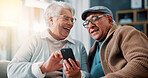 Senior couple, phone and laugh on sofa in home with meme, streaming and funny video on web in lounge. Elderly man, woman and relax with smartphone, joke and social media in retirement at apartment