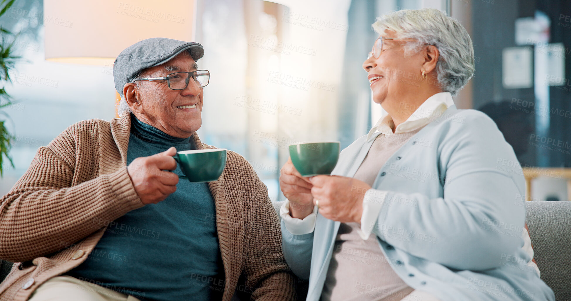 Buy stock photo Happy old couple, talking and drinking coffee in home for relax, story and enjoy latte together. Senior man, woman and tea cup in living room for retirement, laughing and morning chat with funny joke