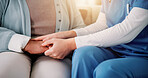 Couch, caregiver and senior patient with holding hands for support, empathy and console for medical news. Home, nurse and old person with consultation for wellness, compassion and flare in closeup
