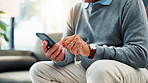 Senior man, hands and typing with phone on sofa for game, word search or social media app at home. Closeup, male person or elderly user browsing with mobile smartphone for connection or network