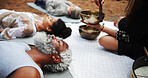 Meditation, sound therapy and woman with bowls in park for mindfulness, spiritual cleanse and energy. Outdoor, ritual and men and women with vibration or frequency for healing, balance and wellness