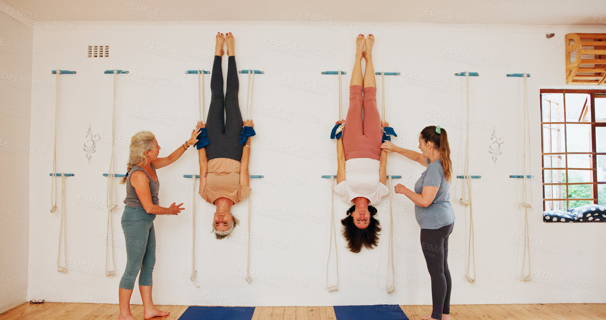 Buy stock photo Stretching, upside down and rope on wall for yoga for senior group or people practice iyengar together in gym class. Women, body health and friends help for wellness, exercise and flexibility at club